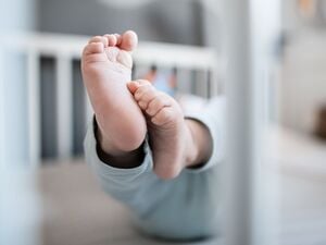 Die Füße eines Babys sind in einem Kinderbett zu sehen.