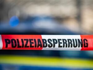 Ein Absperrband mit der Aufschrift Polizeiabsperrung ist vor einem Polizeiwagen aufgespannt.
