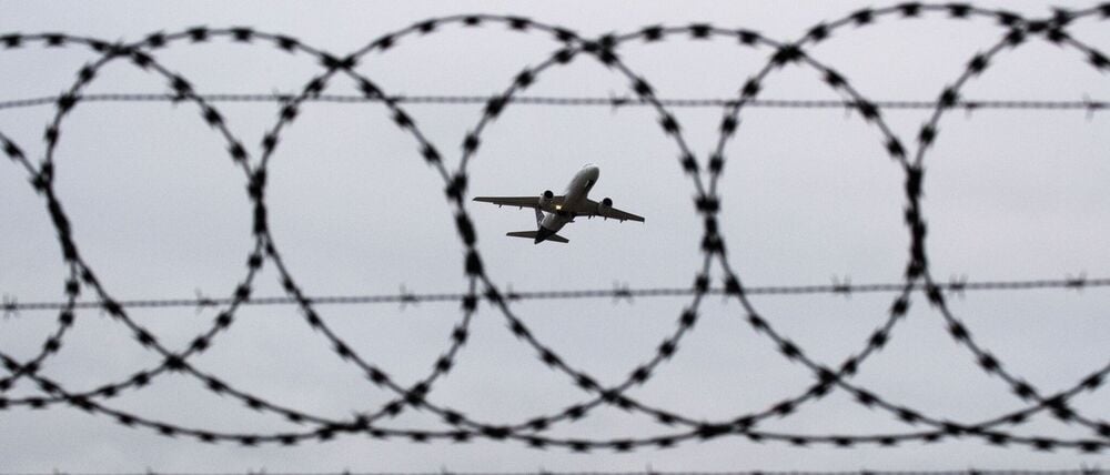 Ein startendes Flugzeug, fotografiert durch Stacheldraht (Symbolbild).