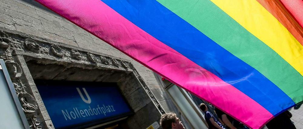 Rot steht für Liebe und Leben, Orange für Gesundheit, Gelb für das Sonnenlicht, Grün für die Natur, Königsblau für Harmonie und Violett für den Geist: Das ist die Regenbogenfahne, das Symbol der queeren Bewegung. Entworfen wurde sie 1978 vom amerikanischen Künstler Gilbert Baker. Schon seit Anfang Juni ist sie am Nollendorfplatz gehisst, in Berlins traditionellem Homo-Kiez.