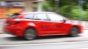 Ein Fahrzeug mit der Werbung von Uber fährt auf einer Straße.