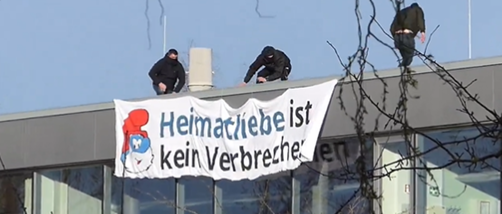 Unbekannte bringen ein Plakat an einer Schule in Ribnitz-Damgarten an.
