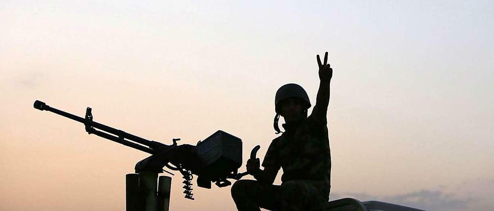 Ein kurdischer Kämpfer gegen die IS-Milizen zeigt im Irak auf einem Autodach.