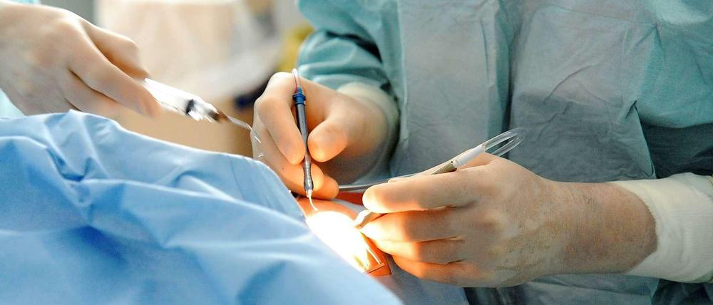 Ein Operateur arbeitet mit chirurgischen Instrumenten an einem Patienten.