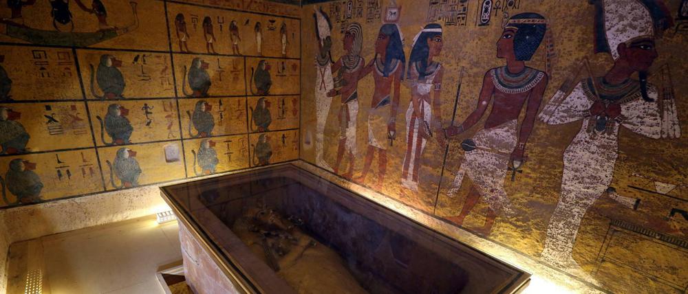 In einer Grabkammer steht ein Sarkophag vor bunt bemalten Wänden.