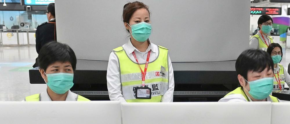 itarbeiter des Hongkonger Gesundheitswesens sollen Reisende am Bahnhof West Kowloon auf ihren Gesundheitszustand hin untersuchen und befragen.