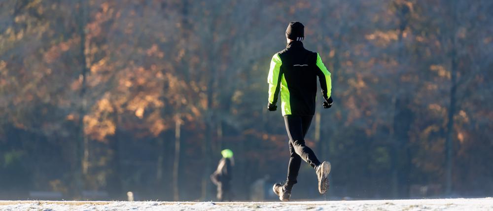 Ein Mann joggt durch den winterlichen Stadtpark.