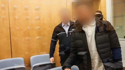 Der Angeklagte (vorne) kommt hinter einer Glasscheibe in den Düsseldorfer Gerichtssaal. Der 42-Jährige soll 2013 eine führende Position beim IS in Syrien eingenommen haben. 