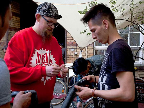 Hein von „Hell Yes! re-Cycling“ hilft Haschemi Ali aus Afghanistan beim Reifenflicken.