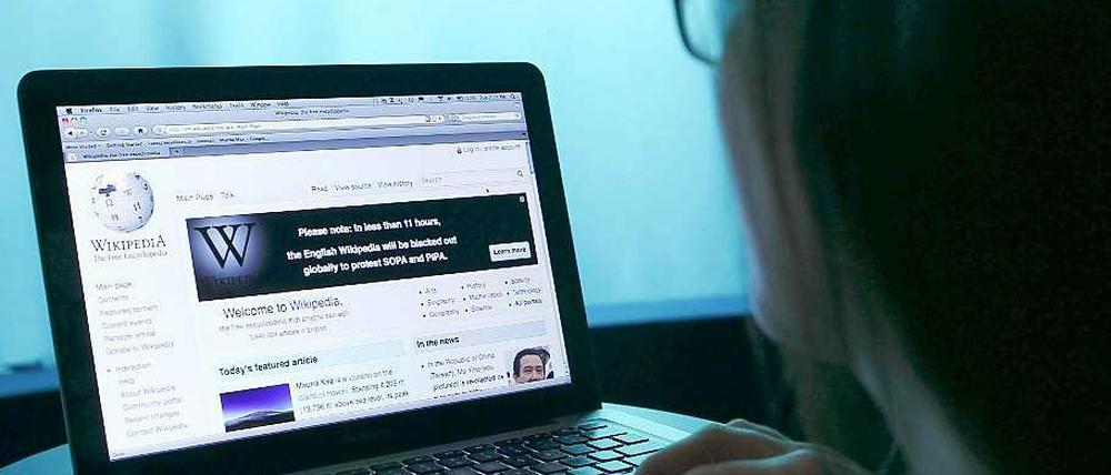 Frau tippt auf Laptop, auf dem Wikipedia geöffnet ist