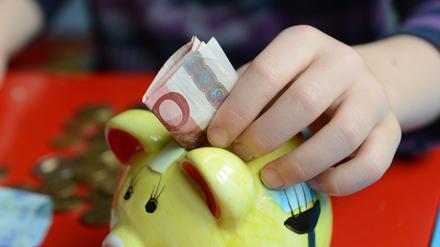 Ein fünfjähriger Junge steckt einen Zehn-Euro-Schein in sein Sparschwein, aufgenommen am 10.04.2012 in Berlin.