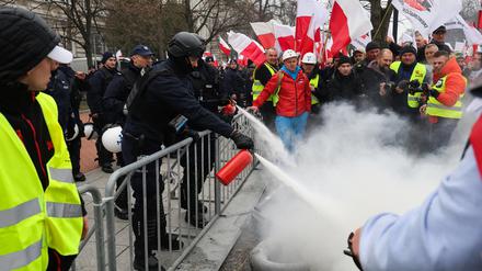 Polnische Einsatzkräfte löschen brennende Reifen, die von Landwirten während der Proteste in Warschau angezündet wurden.