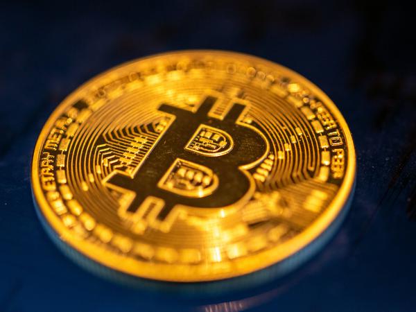 Eine Bitcoin-Münze liegt auf einem Bildschirm.
