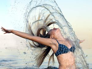 Frau verspritzt Wasser mit ihren Haaren.