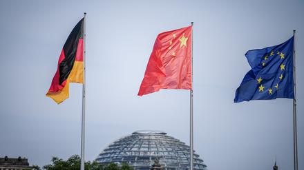 Die Flaggen Deutschlands, Chinas und der EU in Berlin, im Hintergrund die Kuppel des Reichstagsgebäudes. Chinesische Investoren schränken nach einer Studie der Unternehmensberatung EY ihre Firmenkäufe in Europa immer weiter ein. 