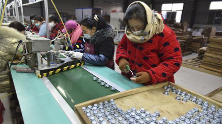 Gegen das kalte Wetter gewappnete Arbeiter montieren Lautsprecher in einer Elektronikfabrik im Bezirk Linquan in der zentralchinesischen Provinz Anhui. 