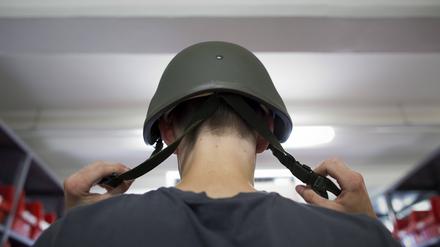 Ein Wehrpflichtiger probiert am ersten Tag seines Wehrdienstes seinen Helm auf. 
