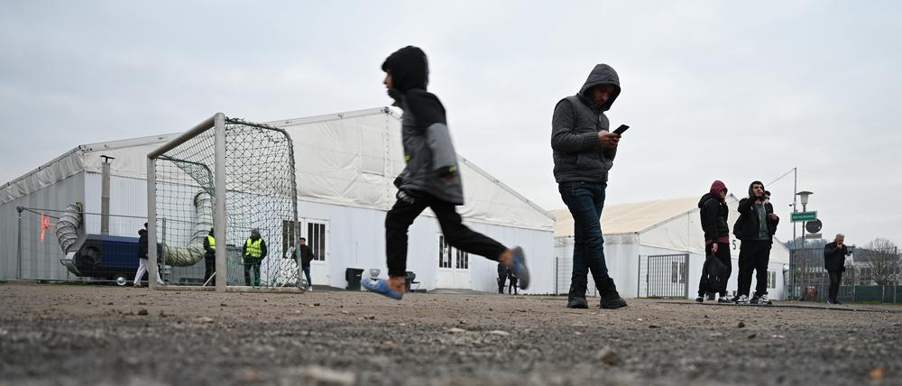 Flüchtlinge halten sich auf dem Gelände einer Flüchtlingsunterkunft vor den Zelten auf. 