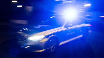 ILLUSTRATION -  Ein Polizeifahrzeug fährt mit Blaulicht an einem Gebäude vorbei. 