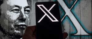 Elon Musk neben einem Handy mit dem X-Logo.