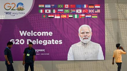 Sicherheitskräfte stehen Wache in der Nähe einer G20-Kommunikationstafel mit dem Konterfei des indischen Premierministers Narendra Modi im internationalen Medienzentrum des G20-Treffpunkts.