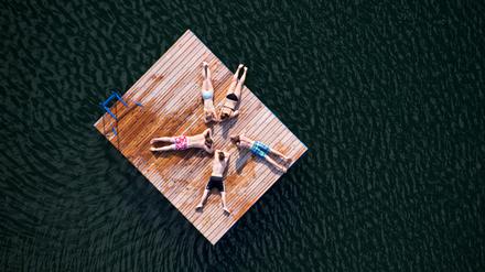 Zwei Mädchen und drei Jungen liegen sternförmig auf einer Holzinsel im Heiseder See bei Sarstedt im Landkreis Hildesheim (Niedersachsen). 