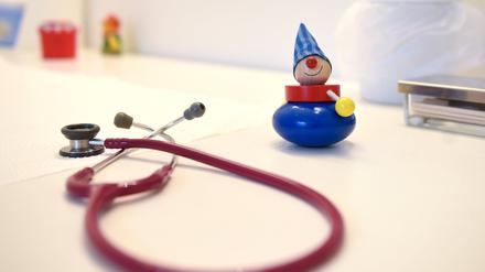 Ein Stethoskop und Kinderspielzeug liegen in einer Kinderarztpraxis auf einem Tisch.