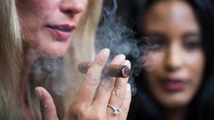 Zwei Models rauchen auf der Messe Intertabac am Stand von Habanos eine Zigarre. 