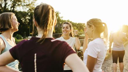 A female fitness group chatting by a canal before beginning a run through the city together.