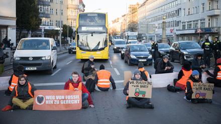 ARCHIV - 10.01.2024, Berlin: Aktivisten der Klimaschutzgruppe Letzte Generation sitzen bei einer Straßenblockade mit Schildern mit aufgemalten Traktoren auf der Straße. Aktivisten nehmen damit Bezug auf die Aktionswoche der Landwirte. (zu dpa: «Gericht: Straßenblockaden von Klimaaktivisten sind Nötigung») Foto: Sebastian Gollnow/dpa +++ dpa-Bildfunk +++