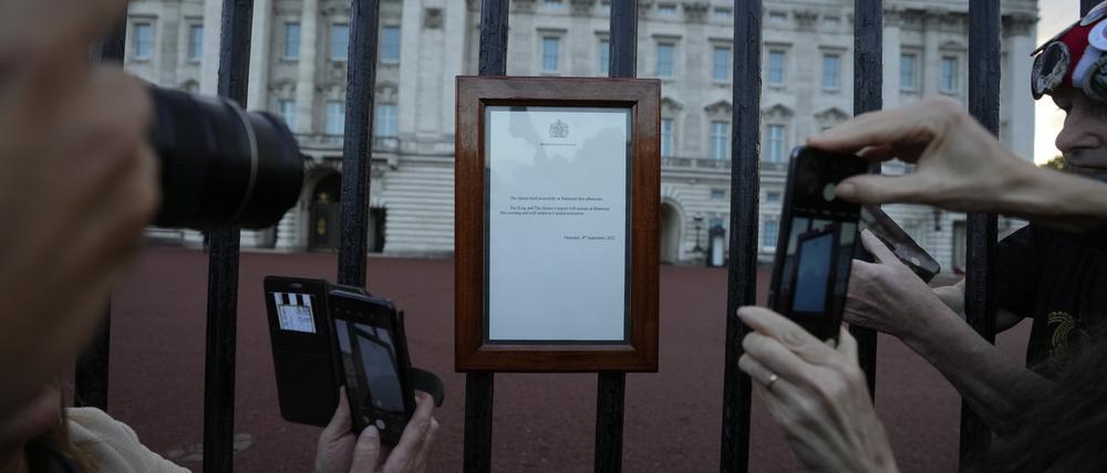 Menschen fotografieren die Bekanntgabe des Todes von Königin Elizabeth II., die an den Toren des Buckingham Palace hängt. 