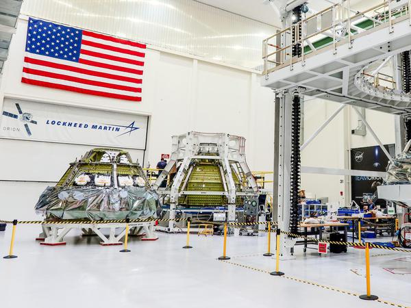 Die Orion-Raumfahrzeuge für die NASA-Missionen Artemis II (r.), Artemis III (l.) und Artemis IV (M) mit Besatzung stehen nebeneinander in der Halle des Kennedy Space Centers der NASA in Florida. Jede Kapsel befindet sich in einem anderen Produktionszustand.