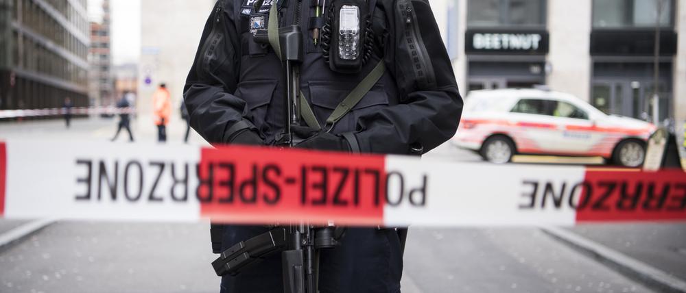 Ein schwer bewaffneter Polizist steht hinter einem Absperrband in der Züricher Innenstadt. 