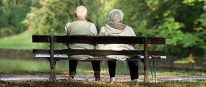 Zwei Rentner sitzen auf einer Bank und genießen ihre Rente. 