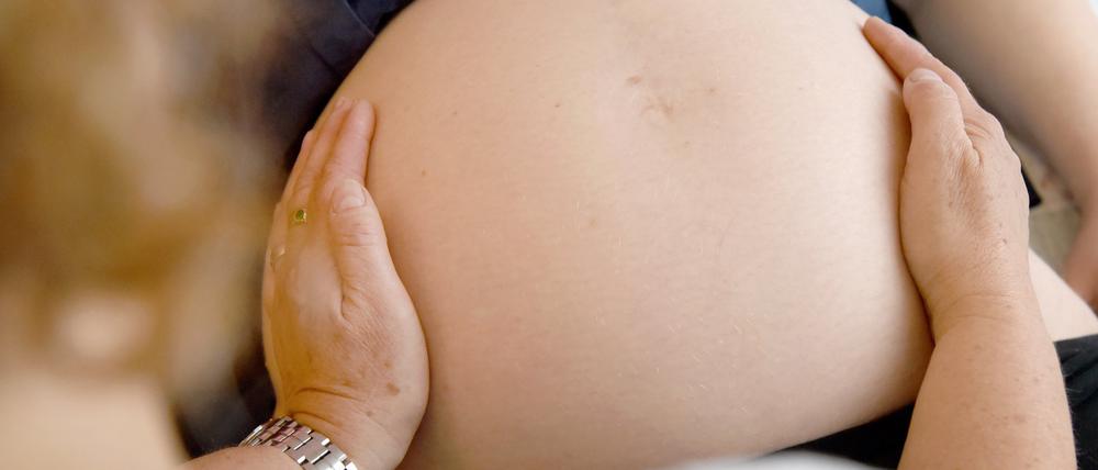 Eine Hebamme tastet den Bauch einer Frau ab, die im neunten Monat schwanger ist. Eine aktuelle Studie hat ergeben, dass hohe Temperaturen während der Schwangerschaft das Risiko einer Frühgeburt erhöhen.