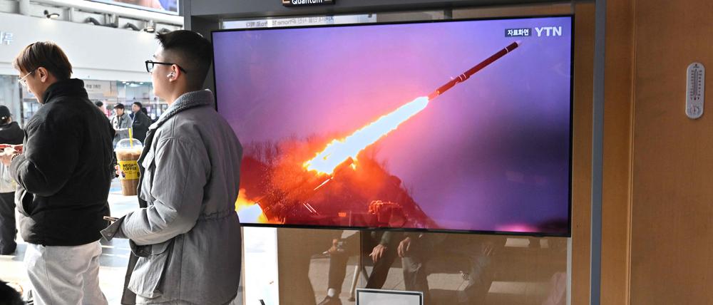 Zwei Männer stehen an einem Bahnhof in Seoul am 2. Februar 2024 neben einem Fernsehbildschirm, auf dem eine Nachrichtensendung mit Aufnahmen eines nordkoreanischen Raketentests gezeigt wird. 