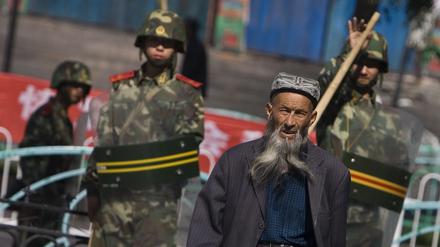Ein Angehöriger der uigurischen Minderheit in China geht in Ürümqi in der Unruheregion Xinjiang vorbei an chinesischen Sicherheitskräften.