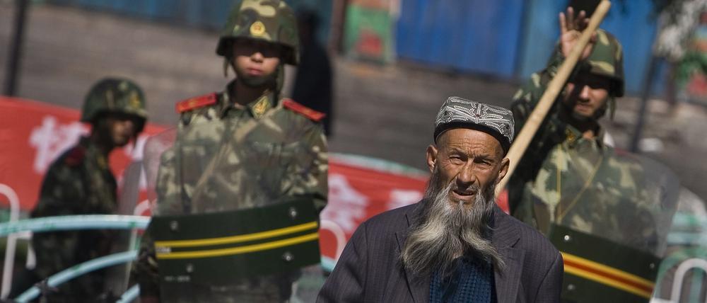 Ein Volk unter Kuratel: Ein Angehöriger der uigurischen Minderheit vor chinesischen Sicherheitskräften in Urumqi (2009)
