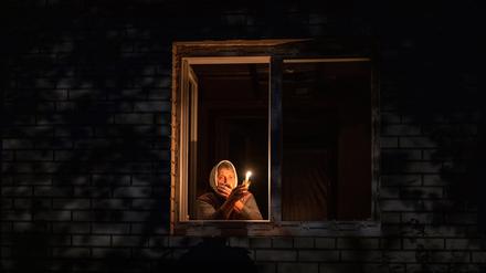Die 70-Jährige Catherine steht während eines Stromausfalls mit einer Kerze in der Hand am Fenster.