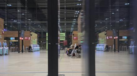 Einige wenige Fluggäste sitzen am frühen Morgen in der Halle des Flughafens BER. Die Gewerkschaft Verdi hat das Bodenpersonal der Lufthansa zu einem ganztägigen Warnstreik an mehreren Flughäfen am Mittwoch aufgerufen. 