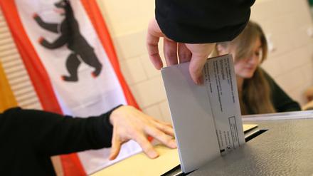 Eine Frau gibt ihre Stimme für die Wahl zum Berliner Abgeordnetenhaus ab und wirft ihren Wahlzettel in die Wahlurne.