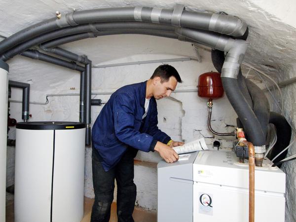 Im Keller eines Einfamilienhauses in Frankfurt (Oder) überprüft ein Handwerker eine Wärmepumpenanlage.