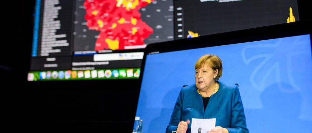 Kanzlerin Angela Merkel bei der Pressekonferenz zum Teil-Lockdown, im Hintergrund die deutsche Corona-Karte