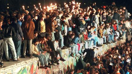 Jubelnde Menschen sitzen mit Wunderkerzen auf der Berliner Mauer am 11.11.1989.