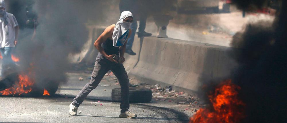 Ein Palästinenser hält am Freitag während der Unruhen Steine in der Hand.