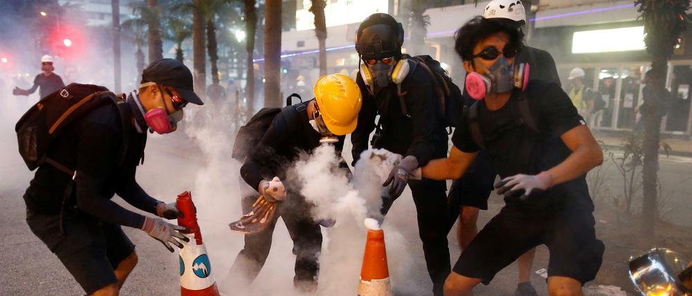 Bei einer Protestkundgebung in Hongkong versuchen Demonstranten, Tränengas-Kartuschen zu löschen.