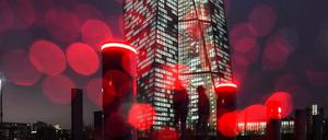 Die rote Beleuchtung von Sperrpollern an der Europäischen Zentralbank (EZB) und Regentropfen auf dem Kameraobjektiv erzeugen am kreisförmige Reflexionen