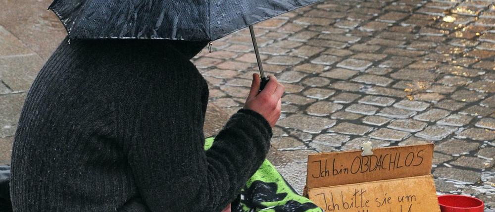 Ein Obdachloser sitzt im strömenden Regen in der Innenstadt von Bremen.