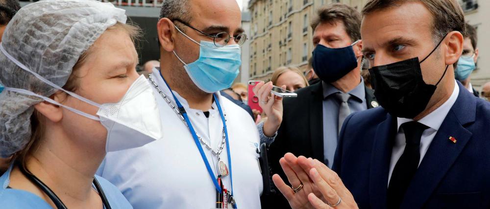 Frankreichs Präsident Emmanuel Macron (rechts) diskutiert in Paris mit Beschäftigten im Gesundheitssektor über deren Arbeitsbedingungen. 