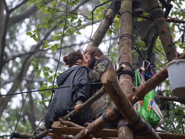 Noch Zeit für Liebe: Aktivisten stehen auf einem dreibeinigen Hochsitz im Hambacher Forst und küssen sich. 